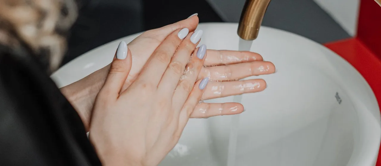 Close-up of hands being washed under a running tap