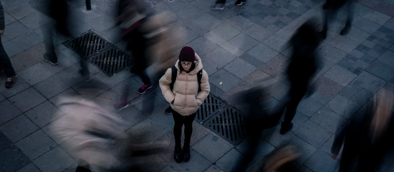 Vrouw staat alleen te midden van een drukke menigte